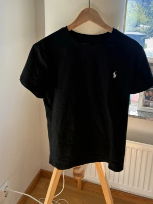 Polo T-shirt  - Plain svart t shirt, säljs pga för liten. Endast använts ca 2 gånger. Skriv i dm vid frågor, vill få den sålt snabbt!