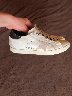Vita golden goose sneakers  - Unisex. Jag säljer dessa golden goose skor åt min lillebror. Han köpte dem förra sommaren och har inte använt dem så mycket. Pris kan sänkas vid snabb affär eller köp av fler