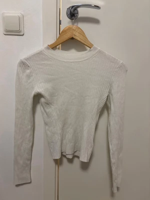 Vit ribbad långärmad tröja från H&M – XS  - Superfin vit ribbad tröja från H&M i storlek XS. Använd endast 1 gång, så den är i mycket fint skick utan några anmärkningar. Den har en figurnära passform och ett mjukt, stretchigt material som är både bekvämt och smickrande. Perfekt att matcha med jeans, kjol eller kostymbyxor – en tidlös baströja som passar till allt! Passa på innan den blir såld! 🤍