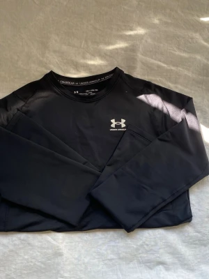 Svart långärmad tröja Under Armour - Säljer en svart långärmad träningströja från Under Armour med rund hals och logga på bröstet. Tillverkad i ett tekniskt material (ColdGear) som passar perfekt för träning i kallare väder. Tight passform och stilren design. Pris kan diskuteras 