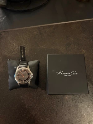 Kenneth Cole klocka - Säljer denna helt oanvända klocka åt min morfar. Klockan kommer från ett lager efter en nedlagd klockbutik och har aldrig använts.  * Skick: Ny/oanvänd * Funktion: Klockan saknar batteri, vilket köparen själv får ordna. * Box och tagg medföljer vid köp. * Nypris: cirka 1300  kr.  Klockan säljs privat och kan skickas eller hämtas efter överenskommelse. Fler bilder kan skickas vid intresse.  Pris kan diskuteras vid snabb affär.