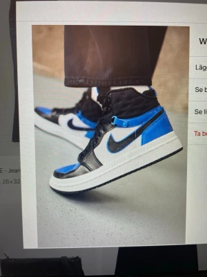 Blå och svarta Nike sneakers - Snygga sneakers från Nike i blått, svart och vitt. Skorna har högt skaft, klassisk swoosh-logga på sidan och en vit sula. Materialet ser ut att vara en mix av läder och textil. Perfekta för dig som vill sticka ut med färg och stil.