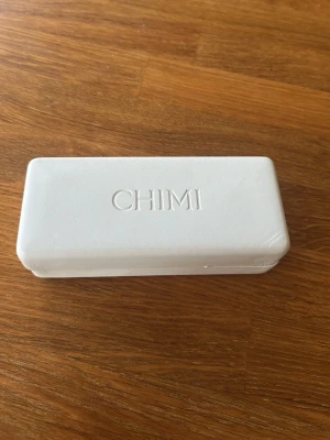  solglasögon från CHIMI - Säljer ett par stilrena nästan helt oanvända solglasögon från CHIMI med transparent, fyrkantig båge och bruna tonade glas. Kommer med ett vitt fodral med CHIMI-logga. Det tillkommer även en putsduk från chimi. Modellen är Core 04. Nypris 1450 från chimis hemsida. 