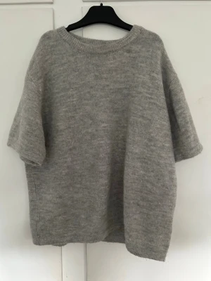 Grå stickad t-shirt Gina Tricot - Säljer grå stickad t-shirt från Gina Tricot (young) med korta ärmar. Tröjan har rund halsringning och ribbade kanter. Köpt för ca 1 år sedan, men använd max 5 gånger. Storlek 170, men passar mig som vanligtvis bär s/m. Köpt för 199kr. 