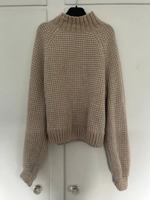 Beige stickad tröja med polokrage - Säljer en beige stickad tröja med polokrage och grovstickat mönster. Tröjan har långa ärmar och ribbstickade muddar vid ärmslut och nederkant. Tröjan är köpt för cirka fem år sedan, men inget täcken på slitage. 