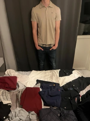 Beige kortärmad pikéskjorta - Snygg beige pikéskjorta med korta ärmar och klassisk krage. Skjortan har knappar framtill och en liten broderad logga på bröstet. Perfekt för en avslappnad men stilren look.