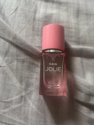 CAIA Jolie parfym rosa flaska - Snygg parfym från CAIA i modellen Jolie. Flaskan är genomskinlig med en rosa ton och har ett matchande rosa lock. Modern och stilren design som passar perfekt på sminkbordet. Eau de Parfum-variant.