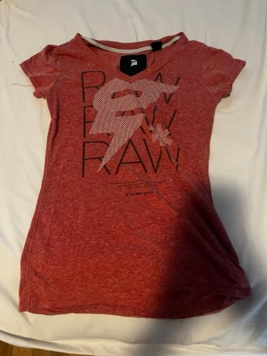 Röd t-shirt från G-Star RAW - Snygg röd t-shirt från G-Star RAW med tryck framtill och rund hals. T-shirten har korta ärmar och är gjord i mjuk bomull. Perfekt för en avslappnad och trendig look.