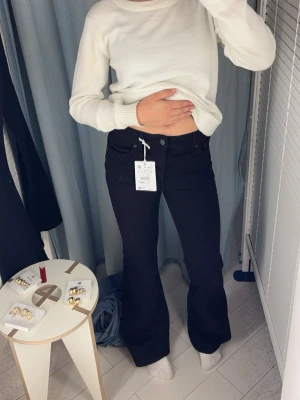 Svarta tall bootcut jeans med hög midja  - Säljer ett par svarta bootcut jeans med hög midja och klassisk femficksdesign. Jeansen har utsvängda ben och stängs med knapp och dragkedja. Materialet är denim med bra strech. 