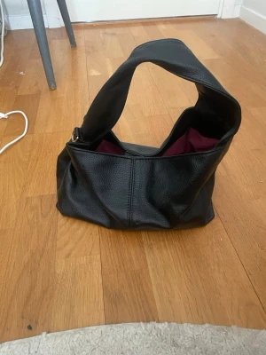 Svart handväska - Ökänt märke, har gått sönder på ena sidan men går att fixa med lite tråd. Annars inga defekter.