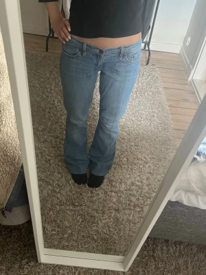 Lågmidjade bootcut jeans - Säljer ett par vintage ljusblå bootcut jeans med klassisk femficksmodell och låg midja. Jeansen har en snygg tvätt och dekorativ söm på bakfickan. Skriv gärna om du har frågor! 
