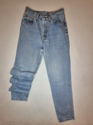 Levi's 901 Vintage Denim – 90-tal  - Svårhittade Levi's 901 vintagejeans tillverkade i Storbritannien under 90-talet. Klassisk mellanblå tvätt med riktigt fin passform och måttligt slitage = patina.                 Mått (cirka): 75cm inre ben, 100cm yttre ben, 22cm gren, 15cm knappgylf, 42cm midja och 20cm fotöppning. Riktigt schysst modell för samlaren eller den som bara vill ha ett par riktigt snygga jeans 😀👍 kolla gärna andra annonser för samfrakt och rabatt. 🌟 skicka meddelande vid frågor om vara eller pris. 