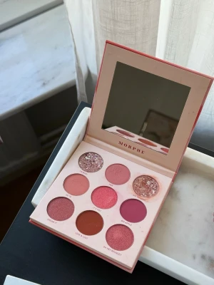 Morphe 9P Petal Passion ögonskuggspalett - Säljer Morphe 9P Petal Passion ögonskuggspalett med nio nyanser i rosa, nude och glittriga toner. Paletten har både matta och skimrande skuggor, perfekt för kreativa sminkningar. Kommer i en snygg rosa förpackning med spegel i locket.
