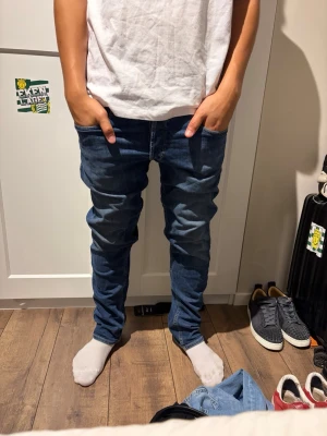 Replay jeans  - Säljer ett par mörkblå slim fit jeans med klassisk femficksdesign och snygga kontrastsömmar. Jeansen har normal midja och smal passform hela vägen ner. Perfekta till sneakers och t-shirt för en avslappnad look.