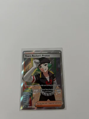 Pokémonkort Team Rocket’s Proton - Säljer ett holografiskt Pokémonkort med motivet Team Rocket’s Proton. Kortet har färger i svart, rött, grönt och silver och är en supporter-trainer från Pokémon TCG. Perfekt för samlare eller Pokémonfans.