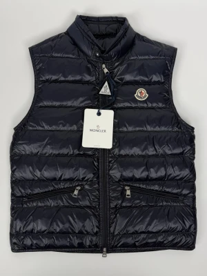Moncler Gui väst marinblå storlek S  - Moncler Gui vest, marinblå. Helt ny med tags aldrig använd. Storlek 1 motsvarar S. Nypris 9.000kr vårt pris 4.990kr | besök vår hemsida Fashionels.com för liknande artiklar. 
