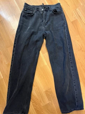 Svarta raka jeans med hög midja - Säljer ett par svarta jeans med rak passform och hög midja. Jeansen har klassiska fem fickor och stängs med knapp och dragkedja. Materialet är kraftig denim i bomull. Perfekta till en avslappnad streetwear-look.