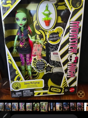 Monster High ,Boo-riginal creeproduktion - Monster High Venus McFlytrap docka i originalförpackning. Dockan har grönt hår med rosa slingor, färgglada kläder och accessoarer. Förpackningen innehåller även en dagbok, växtfigur och väska. Perfekt för samlare eller Monster High-fans.