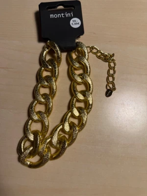 Guldfärgat chunky halsband Montini - Snyggt chunky halsband från Montini (ur&penn)  i guldfärgad metall. Halsbandet har stora, ovala länkar med en glittrig, texturerad yta och justerbar kedja för perfekt passform. Perfekt accessoar för att lyfta din outfit.