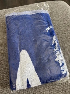 Blå strandhandduk från Umbro - Ny i förpackning. De andra fotona är på en använd handduk, ville inte ta ur den ur förpackningen. Så det är finare färgen på den nya. 