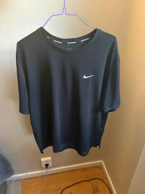 Svart Nike Running Dri-FIT t-shirt - Snygg svart t-shirt från Nike Running med Dri-FIT-material som andas. Klassisk passform med rund halsringning och korta ärmar. Diskret Nike-logga på bröstet. Perfekt för löpning eller träning.