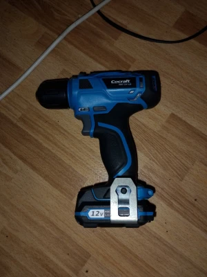 Blå sladdlös borrmaskin Cocraftb HDE 12V LI - Säljer en blå och svart sladdlös borrmaskin från Cocraft, modell HDS 12V-Li. Maskinen har ett ergonomiskt handtag med gummigrepp, metallklämma och tydlig 12V batteriindikator. Perfekt för hemmafix och DIY-projekt. 1,5ah batteri och laddare medföljer. Allt fungerar utmärkt och är i väldigt bra skick!