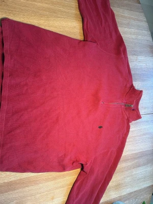 Röd halvzip tröja från Polo Ralph Lauren - Röd långärmad tröja från Polo Ralph Lauren med halv dragkedja och liten broderad logga på bröstet. Tillverkad i mjukt bomullsmaterial och har en avslappnad passform. Perfekt för en chill och stilren look. Är storlek XL men används som l 