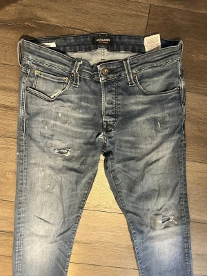 Blå jeans från Jack & Jones - Säljer ett par blå jeans från Jack & Jones med slitningar. Vid frågor är det bara att skriva 