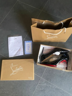 Svarta lackpumps från Louboutin - Säljer ett par klassiska svarta pumps från Christian Louboutin i glansigt lackläder. Skorna har spetsig tå och den ikoniska röda sulan. Perfekta för dig som vill ha en elegant och tidlös look. Levereras med originalkartong och påse.