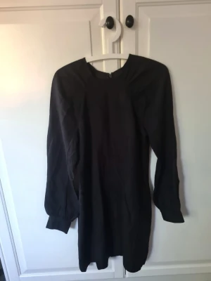  Linn Svart långärmad klänning H&M - En svart, enkel och stilren klänning från H&M i storlek 40. Klänningen har långa ärmar, rund halsringning och dragkedja i ryggen. Passar perfekt till dig som gillar minimalistisk stil och vill ha en klassisk bas i garderoben.