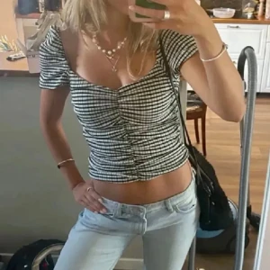 Rutig blus med puffärmar - Supersöt svartvit rutig blus med puffärmar och snörning framtill. Figurnära passform och perfekt att styla med jeans eller kjol! 🥰