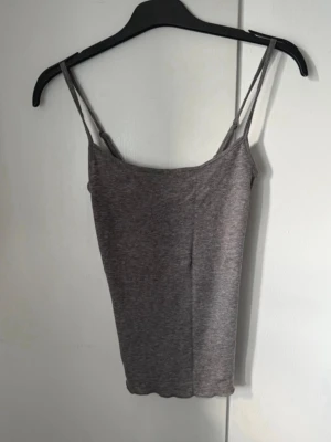 Grå linnetopp från BikBok - Snygg grå linnetopp från BikBok i mjukt material. Toppen har smala axelband och en enkel, rak passform som passar perfekt till jeans eller kjol. Stilren och enkel att matcha med olika outfits. Woolblend ullblandning 