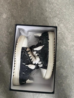  denim sneakers från Nummeris  - Snygga sneakers från Number 15 med mörkblå  slitstarkt denimtyg och vita detaljer i läder. Skorna har chunky vit sula, breda vita skosnören och låg profil. Perfekt för dig som gillar en streetwear vibe och vill sticka ut med en unik look.