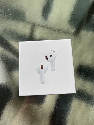 Apple AirPods 3 med laddningsetui - Säljer ett par vita Apple AirPods 3 med trådlöst laddningsetui. Hörlurarna har en stilren och kompakt design i blank plast och levereras i originalförpackning. Perfekta för musik, samtal och träning med smidig anslutning till iPhone och andra Apple-enheter.