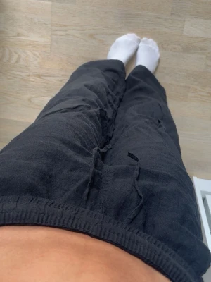 Svarta linnebyxor med resårmidja - Säljer ett par svarta linnebyxor med avslappnad passform och resår i midjan. Byxorna har raka ben och sidofickor, perfekta för en chill och stilren look. Materialet är luftigt linne som känns skönt mot huden.