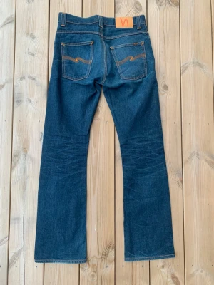 Nudie Jeans Regular Ralf Discontinued - Riktigt fina nudie jeans I modellen regular ralph som inte längre säljs. Jeansen har en bootcut passform och är i w29, utgå alltid från angivna mått! Midja: 40, Ytterben: 107, Innerben: 78 Benöppning: 22