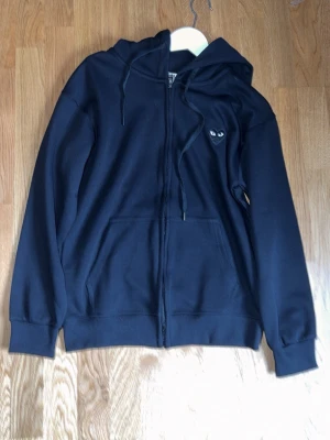 Svart hoodie med hjärta och ögon - Svart hoodie med dragkedja från Comme des Garçons Play Storlek S men kan passa M XS beroende på sin style aldrig använd.