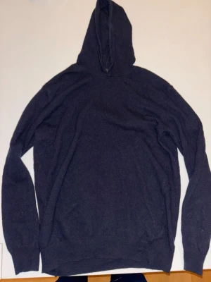 Mörkblå hoodie från Oscar Jacobson - Mysig mörkblå hoodie från Oscar Jacobson i mjukt stickat material. Klassisk modell med huva och långa ärmar. Perfekt för dig som gillar stilrena och bekväma plagg med en enkel look.