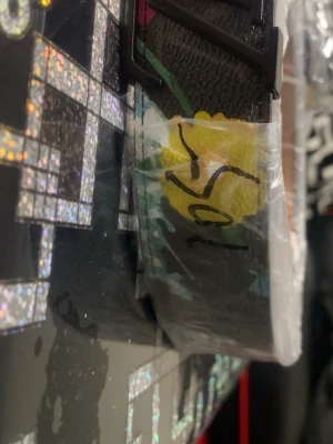 Färgglatt bälte med blommönster - Snyggt bälte med färgglada blommor och grafiska detaljer i flera nyanser som gul, rosa, blå och lila. Bältet har ett svart spänne och är tillverkat i ett material som liknar skinn. Perfekt för att ge outfiten en unik touch.