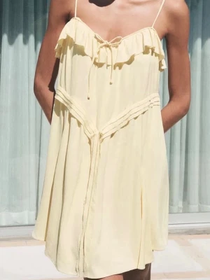 Ljusgul kort klänning från Zara storlek S - Supersöt ljusgul klänning från Zara med tunna axelband och volangdetaljer upptill. Vet inte vad original priset är men säljer för 100kr. Klänningen har en knytning vid bröstet och är tillverkad i ett lätt och luftigt material, perfekt för varma dagar.