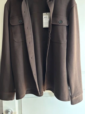 Overshirt från only & sons - Säljer en stilren overshirt med två stora bröstfickor med knappar och klassisk krage. Overshirten har långa ärmar och är tillverkad i ett kraftigt material som ger en snygg struktur. Perfekt att bära som lager över t-shirt eller hoodie.