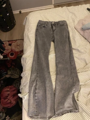 Grå bootcut jeans med vintage-look - Säljer ett par grå bootcut jeans med snygg vintage-wash och klassisk femficksdesign. Jeansen har hög midja och raka ben som slutar i en lätt utsvängning. Perfekta för dig som gillar en avslappnad och trendig stil.