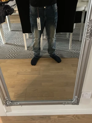 Blå jeans från Purple med tvättad look - Säljer ett par blå jeans från Purple med cool tvättad effekt och snygga detaljer. Jeansen har klassisk femficksdesign och en modern passform som sitter bra. Materialet är denim och färgen är blå med ljusa partier. Perfekt för dig som vill ha en trendig stil.