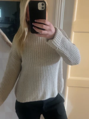 Beige stickad tröja  - En stilren beige stickad tröja med rund hals och långa ärmar. Tröjan har en grovstickad struktur och är perfekt för att hålla sig varm under kyliga dagar. 
