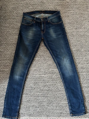 Nudie jeans - Säljer ett par blå slim jeans från Nudie Jeans med snygga slitningar.