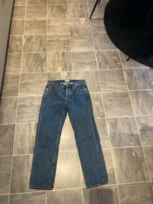 Blå Lager 157 straight jeans - Säljer ett par klassiska blå Levi's jeans med raka ben och fem fickor. Jeansen har normal passform och är tillverkade i slitstarkt denim-material. Perfekt för dig som gillar tidlös stil och vill ha ett par jeans som funkar till allt.