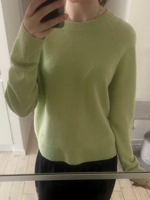 Ljusgrön kashmir tröja - En stilren ljusgrön kashmir tröja med rund halsringning och långa ärmar. Tröjan har ribbstickade muddar vid ärmslut och nederkant, vilket ger en snygg och enkel look. Perfekt för lager-på-lager och passar till många outfits.