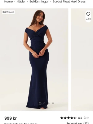 Marinblå Bardot långklänning - Elegant marinblå långklänning med bardot-axlar och figurnära passform. Klänningen har omlott-detaljer upptill och en lång, smal siluett som ger en stilren look. Perfekt för speciella tillfällen när du vill känna dig extra fin.