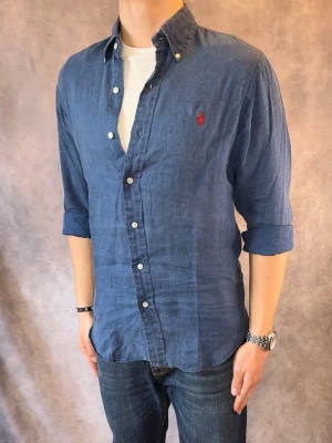 Blå Ralph Lauren Linneskjorta - Stl S, Slim fit - RIKTIGT FET LINNESKJORTA FRÅN RALPH LAUREN I FÄRGEN blå/marinblå med röd pony, perfekt till sommaren som närmar sig! 🏖️🌊 | Mycket bra skick: 9/10, utan defekter!, minimalt urtvättad | Stl: S |  Modellen är 177cm och väger 74kg,  | Hör av dig vid frågor // Galgen 🫡