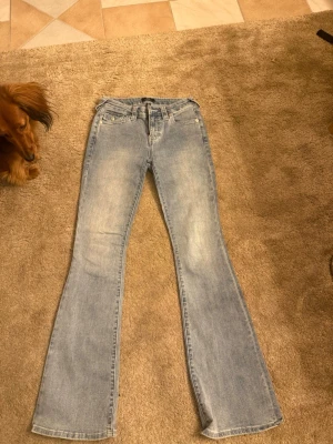 Ljusblå bootcut jeans - Säljer ett par ljusblå bootcut jeans med klassisk femficksmodell och utsvängda ben. Jeansen har en snygg tvättad look och normal midja.
